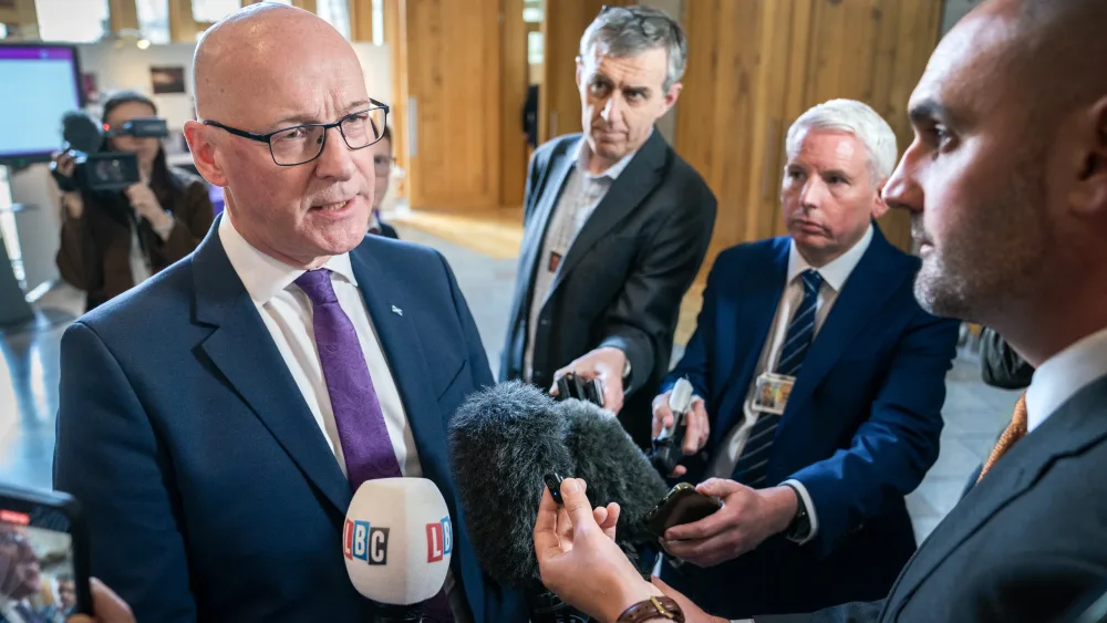 John Swinney speaking amongst a group of journalists