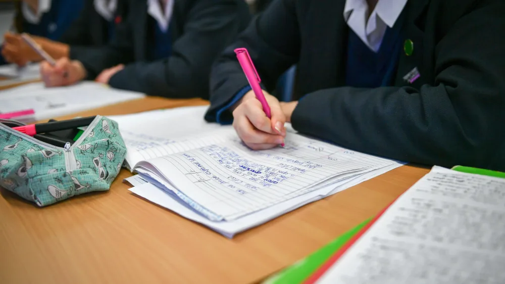 Pupils working in jotters, seated in class