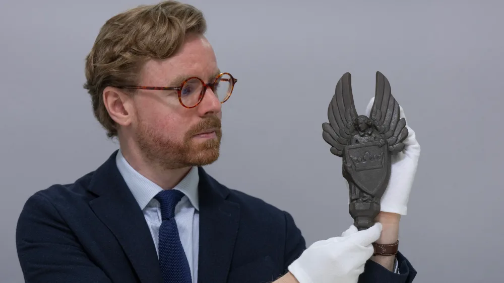 Curator Dr Calum Robertson holding a cast iron angels