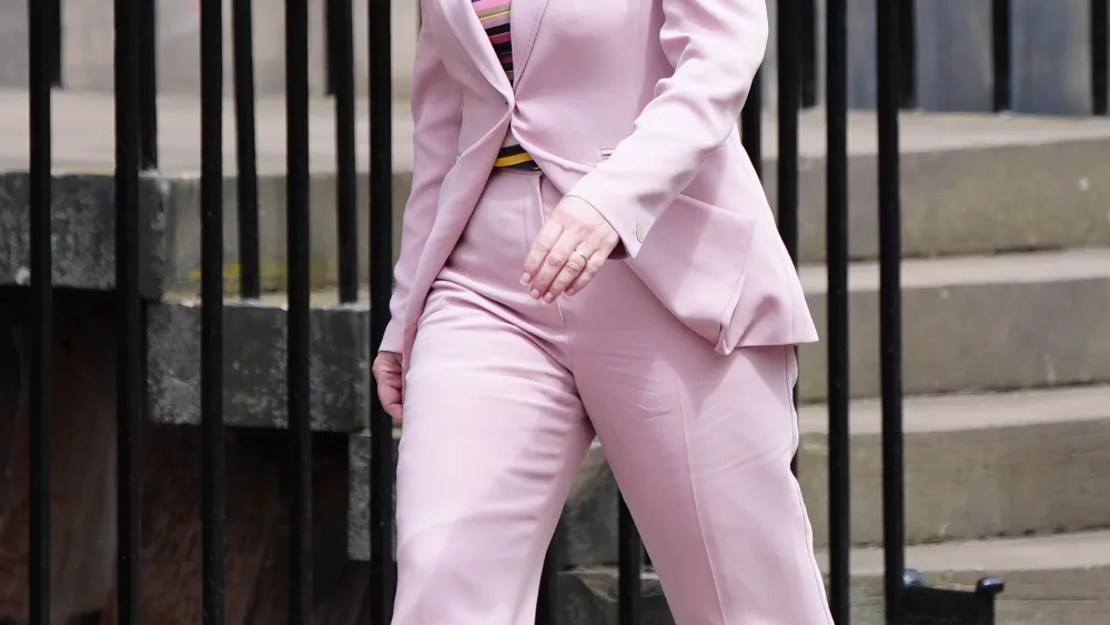 Gillian Martin walking along a pavement, wearing a powder pink suit