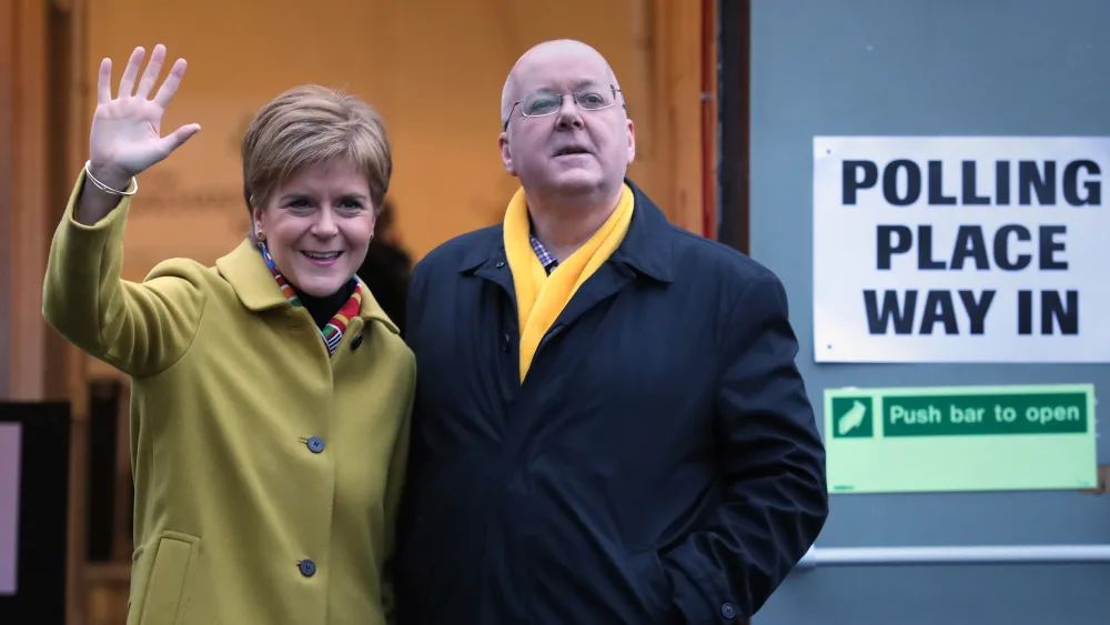 Nicola Sturgeon and Peter Murrell wave to the media after casting their vote
