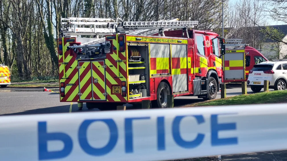A view of a fire engine parked on a street, behind police tape