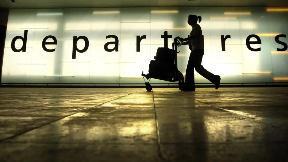 A passenger pushing a luggage trolley beside a large sign reading 'departures'