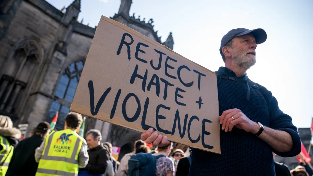 A man holding a sign reading 'Reject hate and violence'