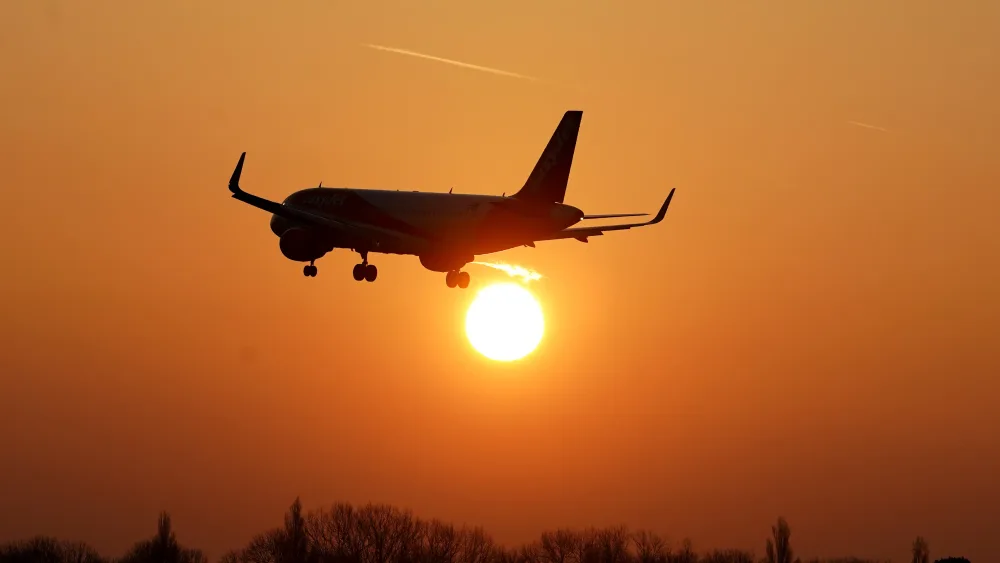 Plane flying against low sun