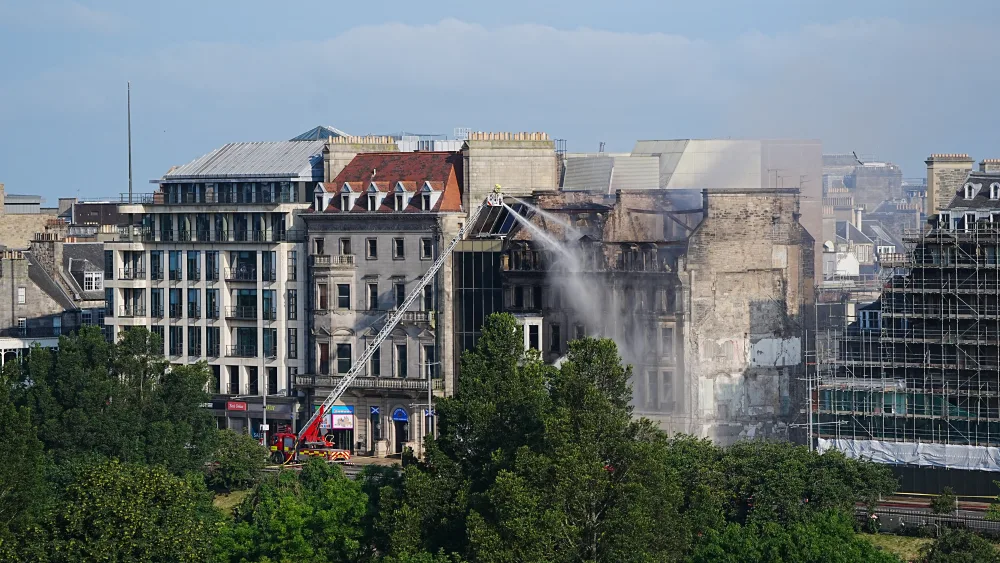 Firefighters working at a building which is blackened and charred