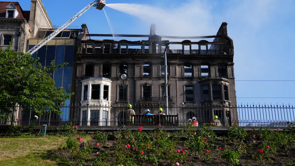 Firefighters on a high platform tackling a blaze in a building, which is blackened