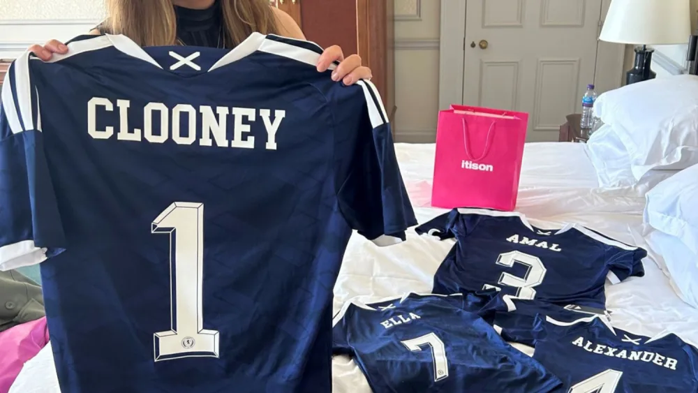 Prize draw winner Claire Phale holds up a Scotland kit with the name Clooney on the back, ahead of gifting it to Hollywood star George Clooney