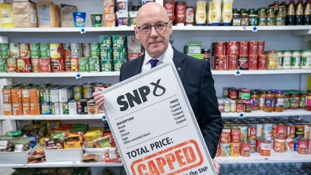 First Minister John Swinney holding placard