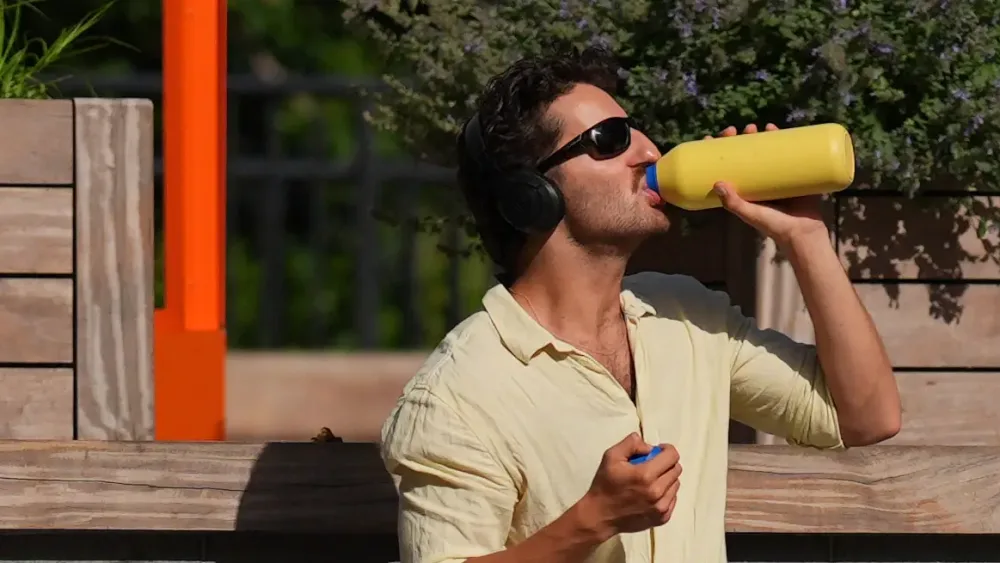 A person drinks from a water bottle in the sun