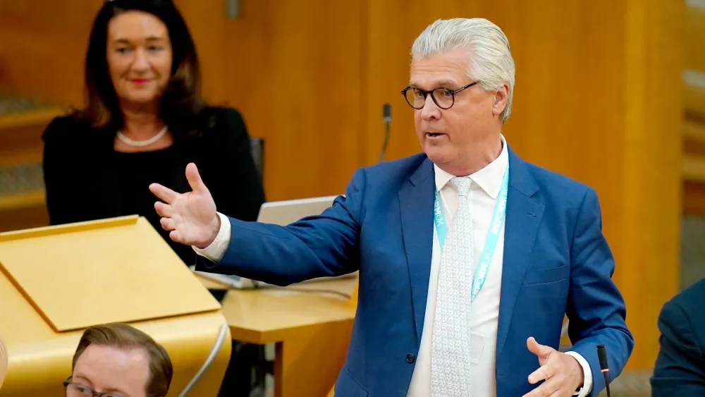 Malcolm Offord gesturing with an arm while speaking in Holyrood