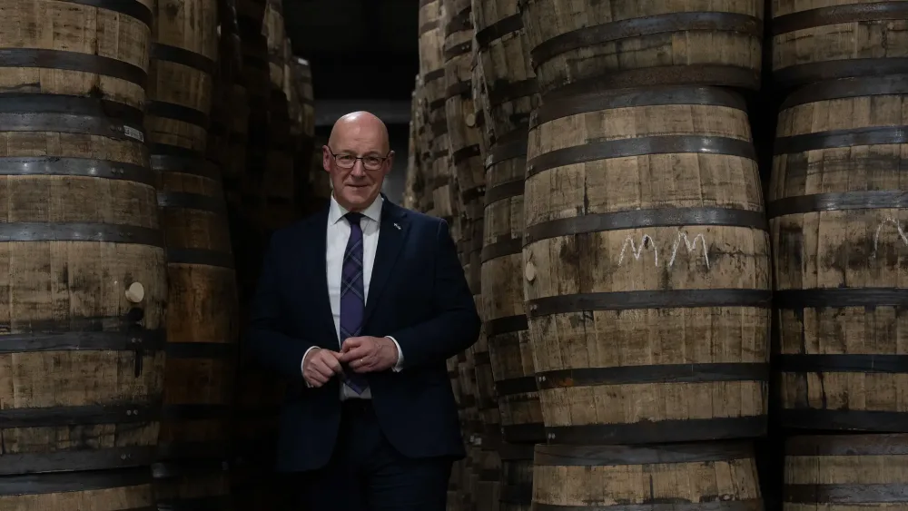 First Minister John Swinney standing among bourbon barrels during a tour in Kentucky