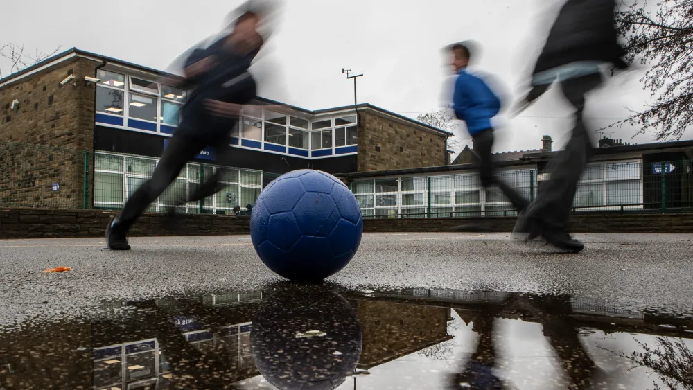 Boys play football during a school break period