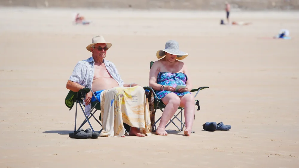 A middle aged couple on a sandy beach in the sunshine