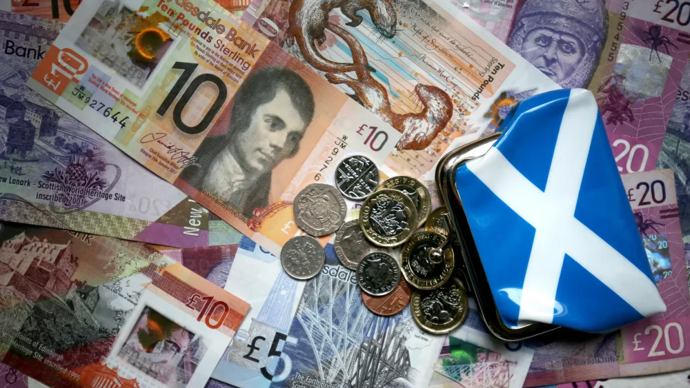 A saltire design purse sits on top of bank notes and coins