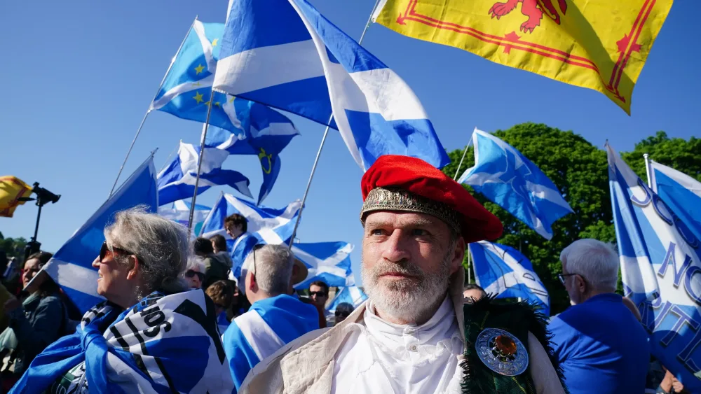 Independence supporters waving Scottish flags, standing outside under blue skies
