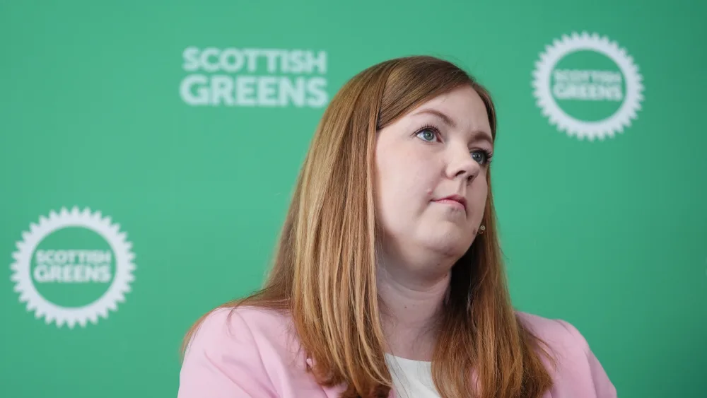 Gillian Mackay seated in front of Scottish Green signage
