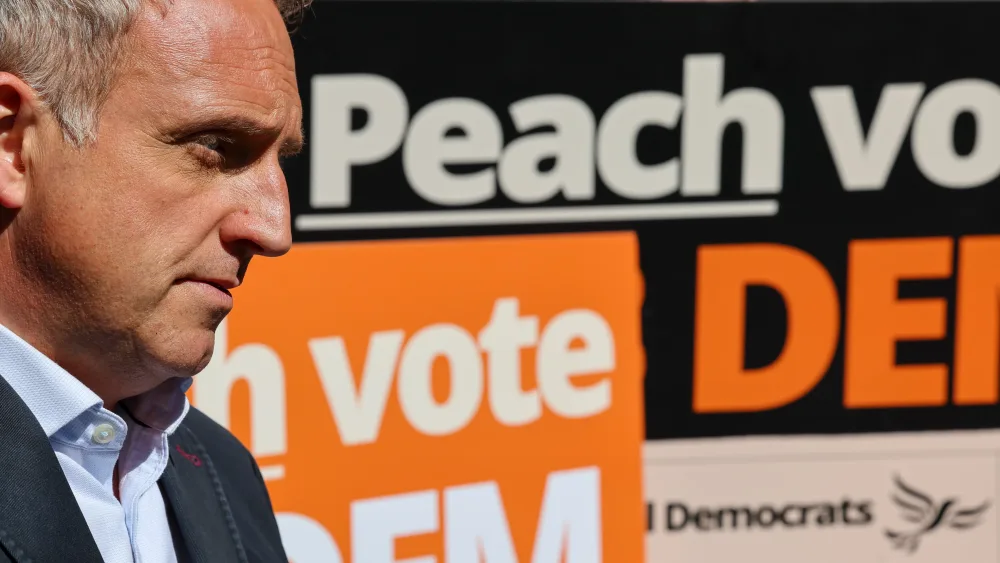 Alex Cole-Hamilton side view next to a Lib Dem election poster