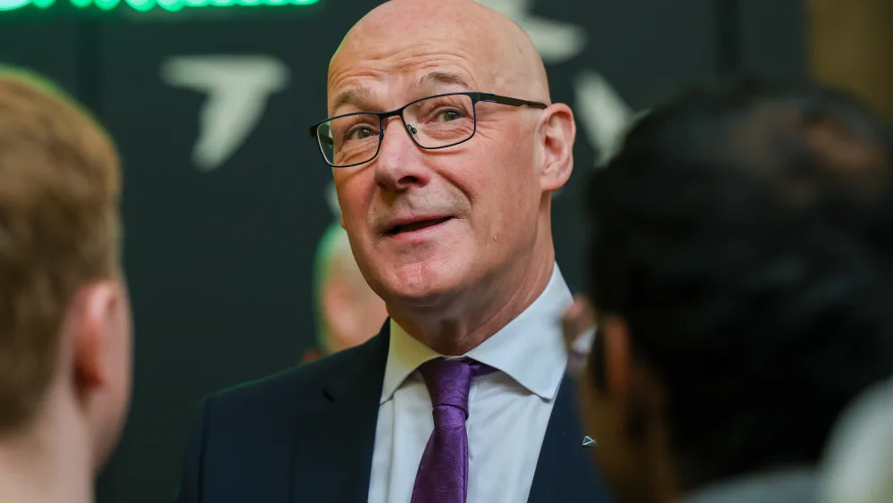 John Swinney speaking, with two young people facing him, away from camera