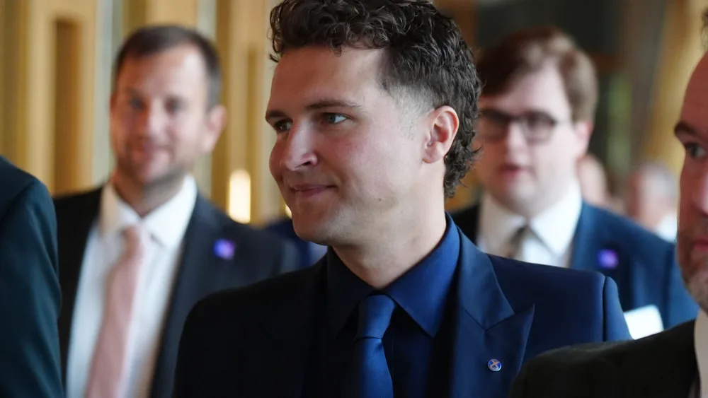 Jack Middleton smiling while walking through a corridor at Holyrood