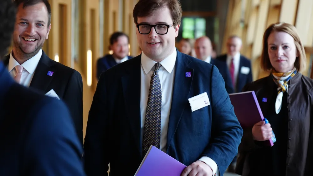 Max Bannerman smiling while walking through a corridor at Holyrood
