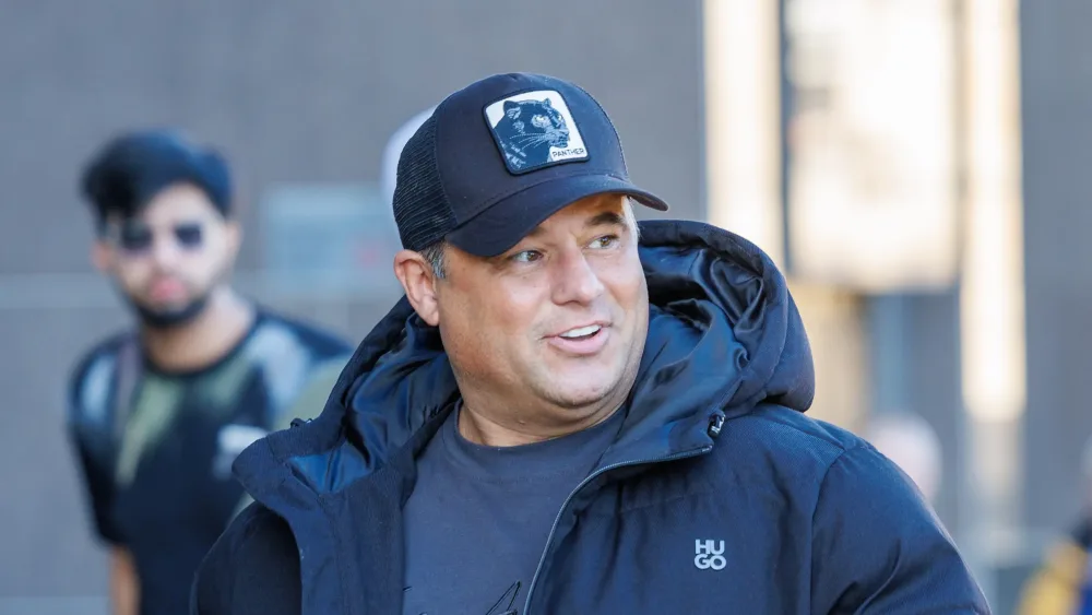 James English walking outside, wearing a baseball cap and coat