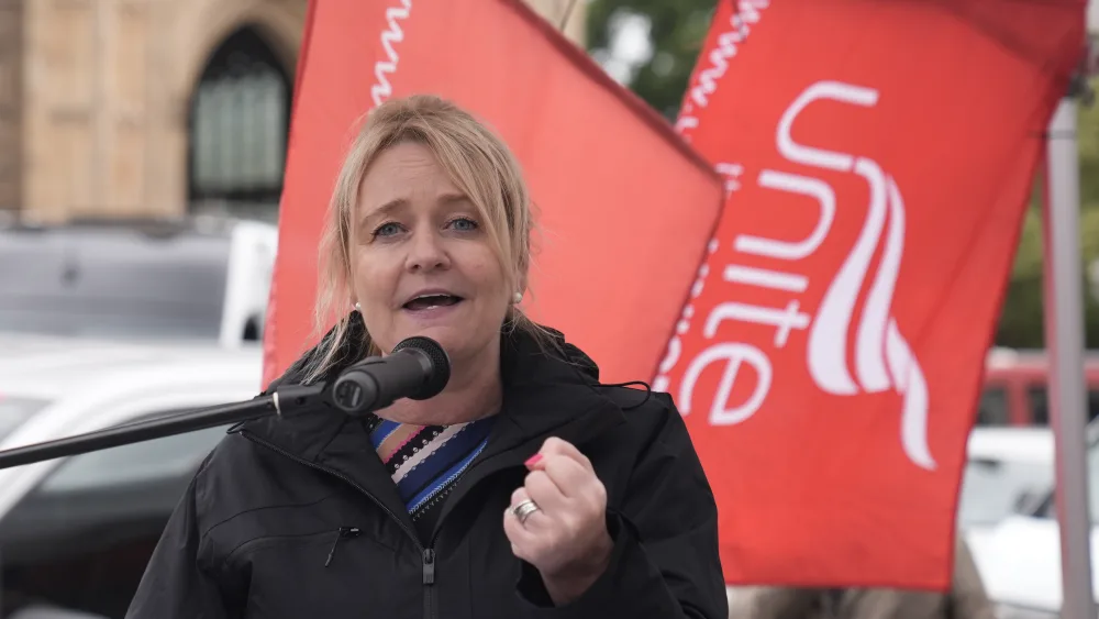 Sharon Graham speaking in front of Unite flags