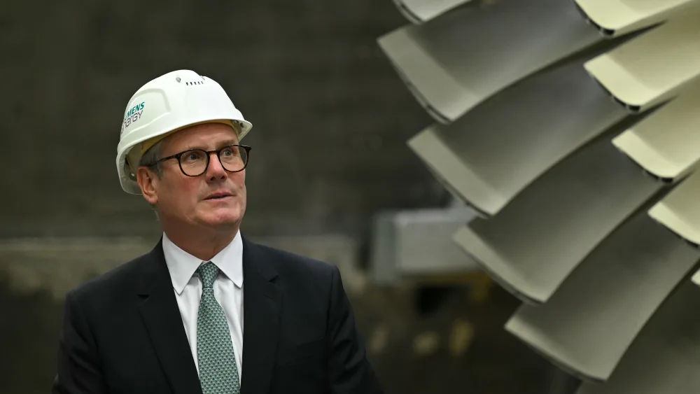 Sir Keir Starmer in white hard hat, standing next to a large fan