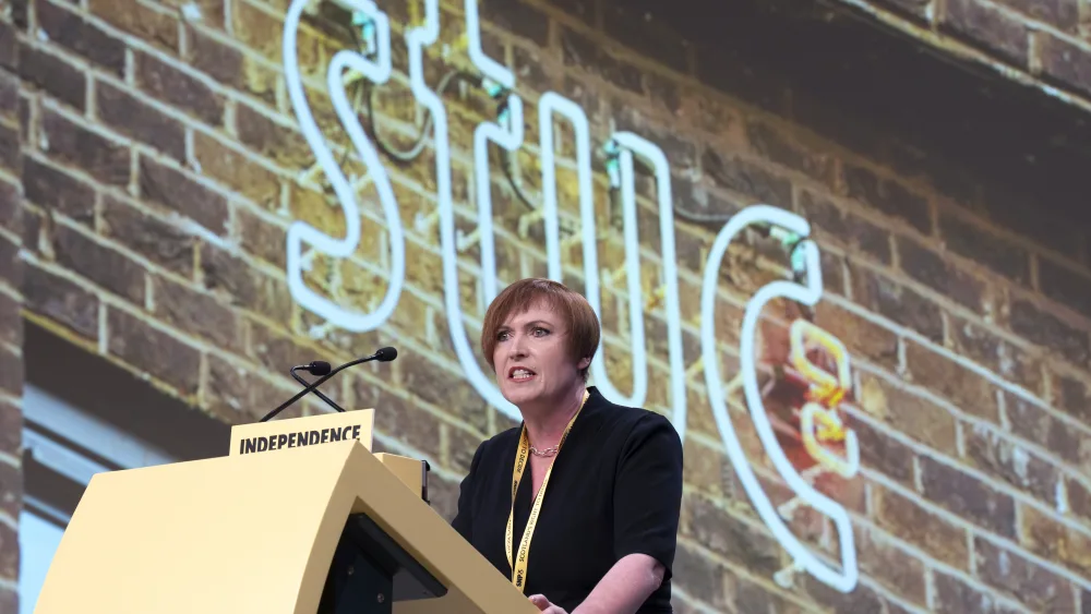 Roz Foyer speaking from a lectern in front of a large STUC sign