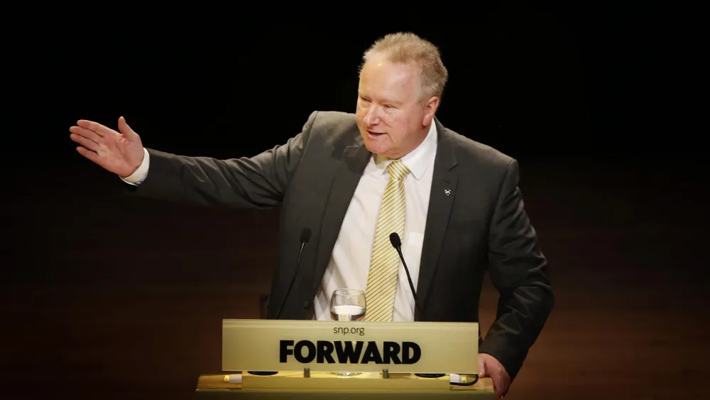Alex Neil waving his hand as he makes a speech