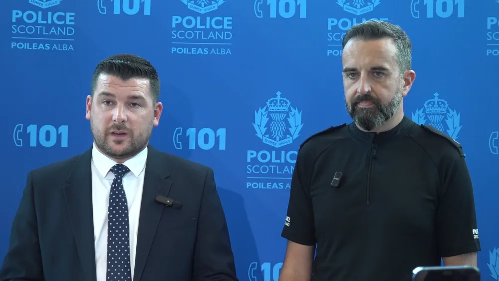 Two senior police officers in front of a blue background