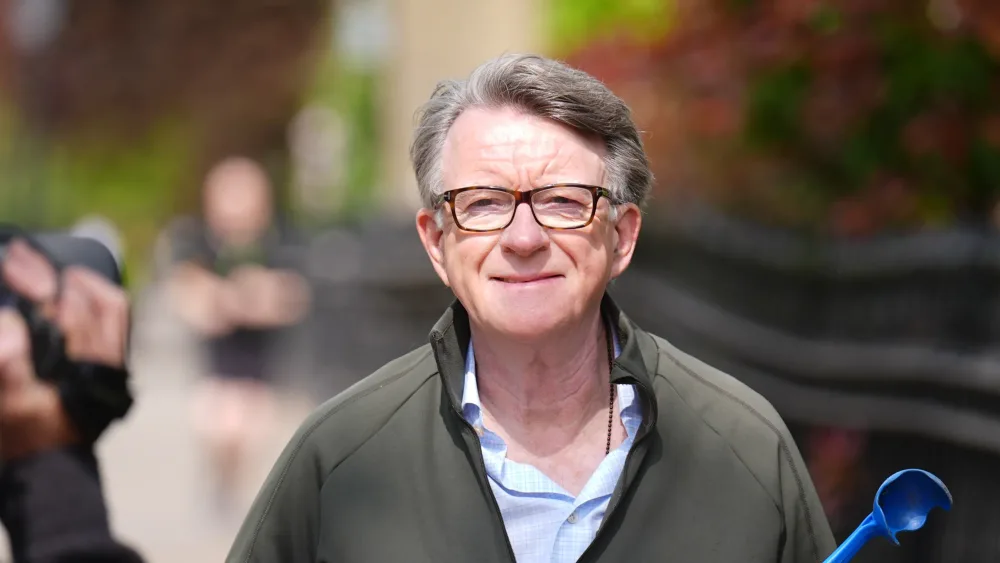 Peter Mandelson smiling while walking outside