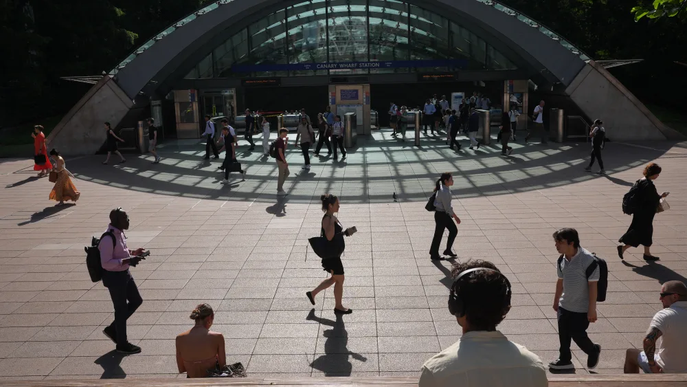 Commuters walking in the sunshine outside a station