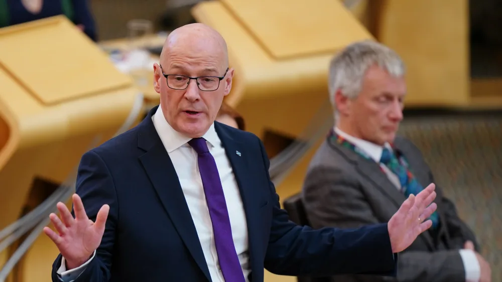 John Swinney standing while speaking in Parliament