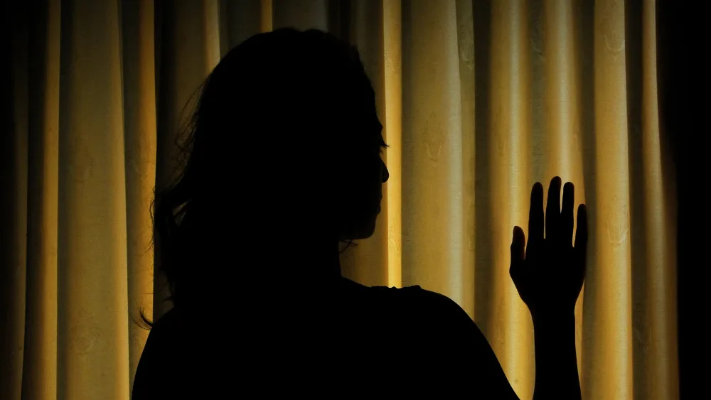 A woman in front of closed curtains