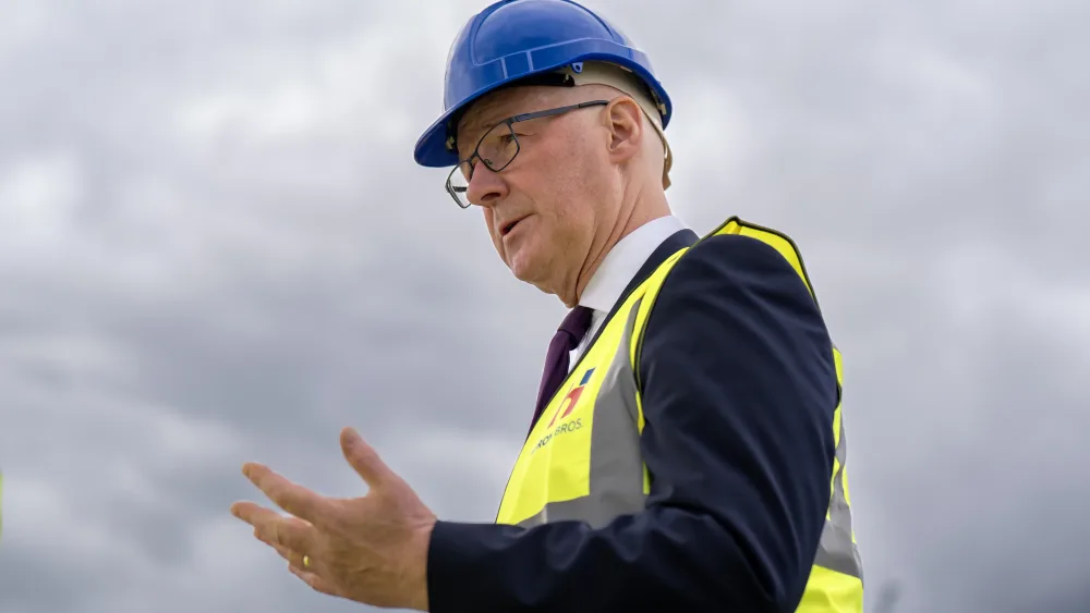Side view of John Swinner, who is wearing a hi-vis vest and hard hat while speaking