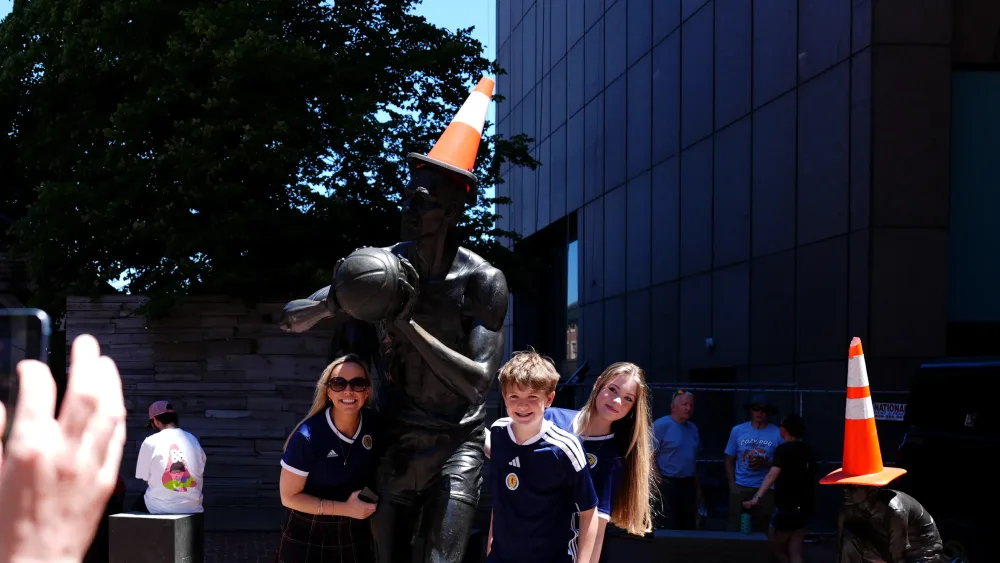 Scotland fans pose in front of a statue with a cone on its head