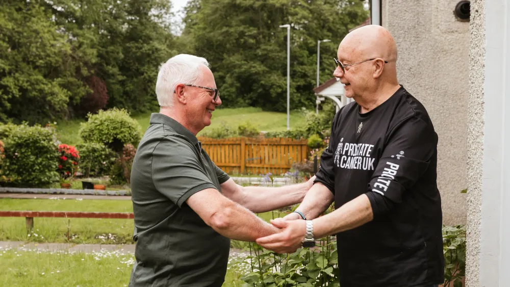 Taxi driver Brian Kelly, left, shaking hands with Prostate Cancer UK volunteer Tam Hewitt in Glasgow