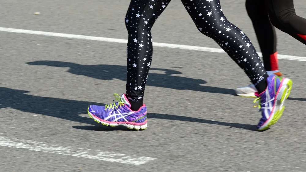 The legs of runners on a road