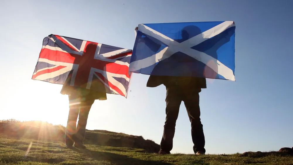 People holding Union and saltire flags stand on Arthur's Seat