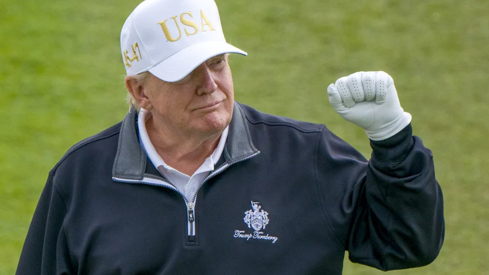 Donald Trump with his fist in the air, on a golf course