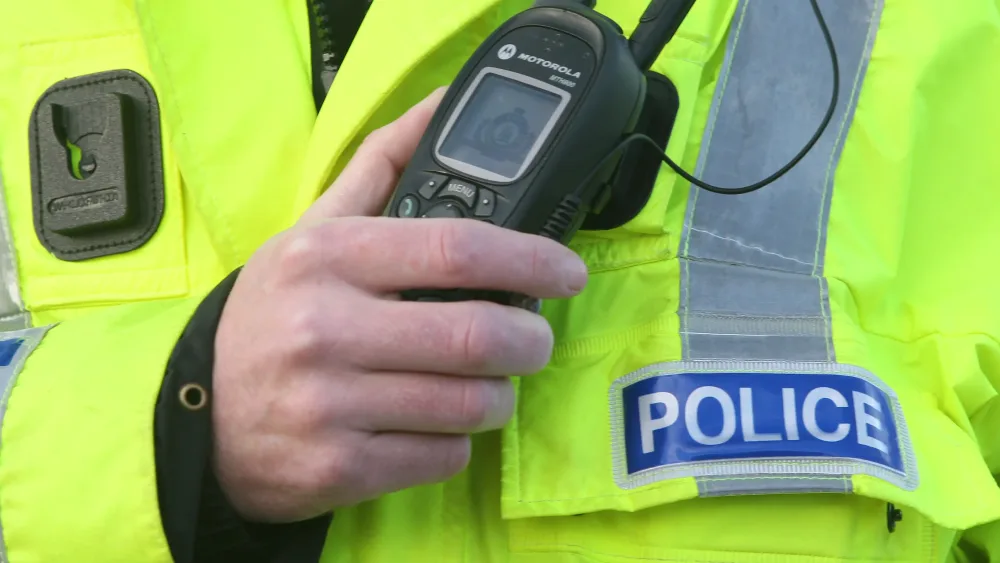 Police officer's hand holding a radio