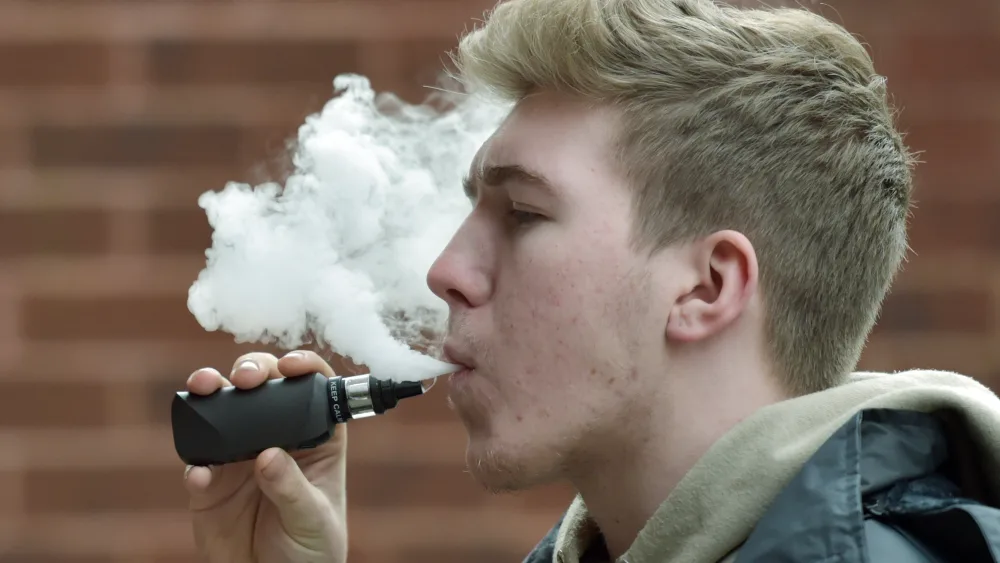 A young man using a vape