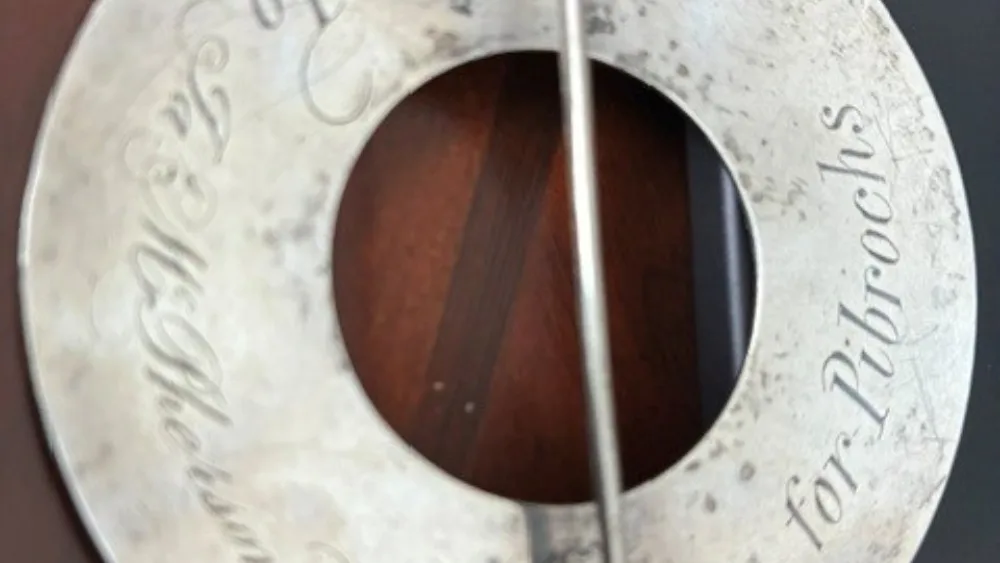 View of the reverse of a silver brooch, which shows an inscription