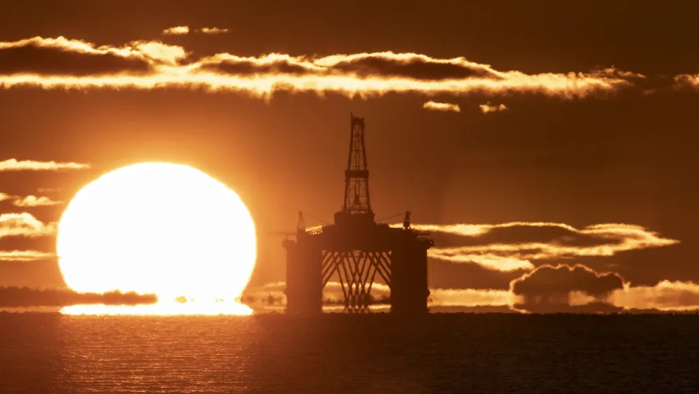 An oil platform at sea, next to the sun rising