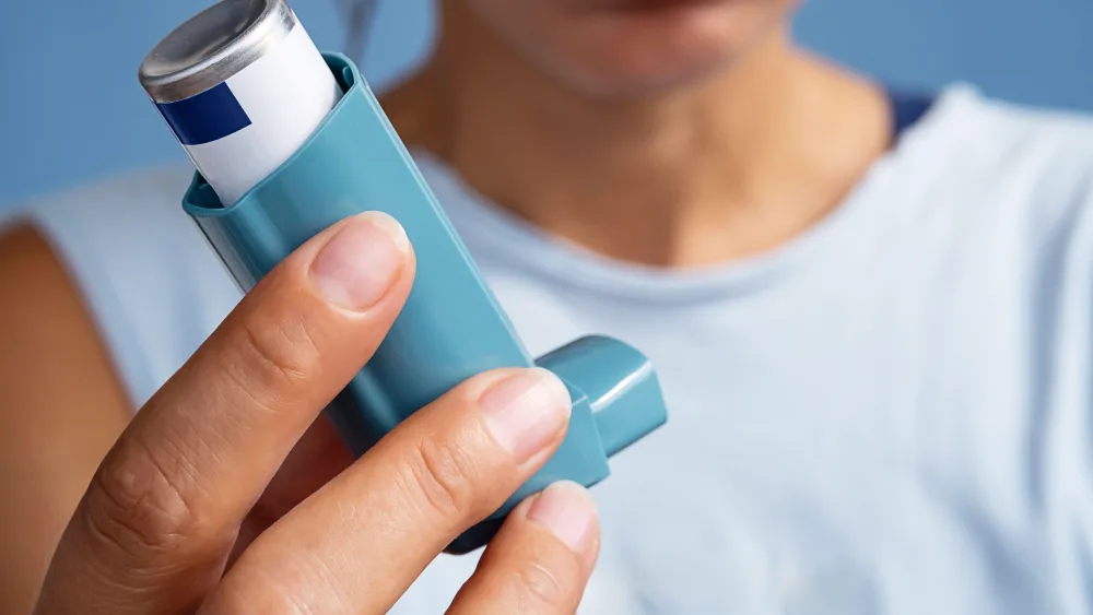Woman holding asthma inhaler.