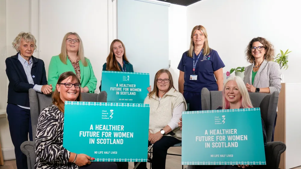 A group of women hold signs about inequalities in women's health to raise awareness for a charity's new women's health action plan