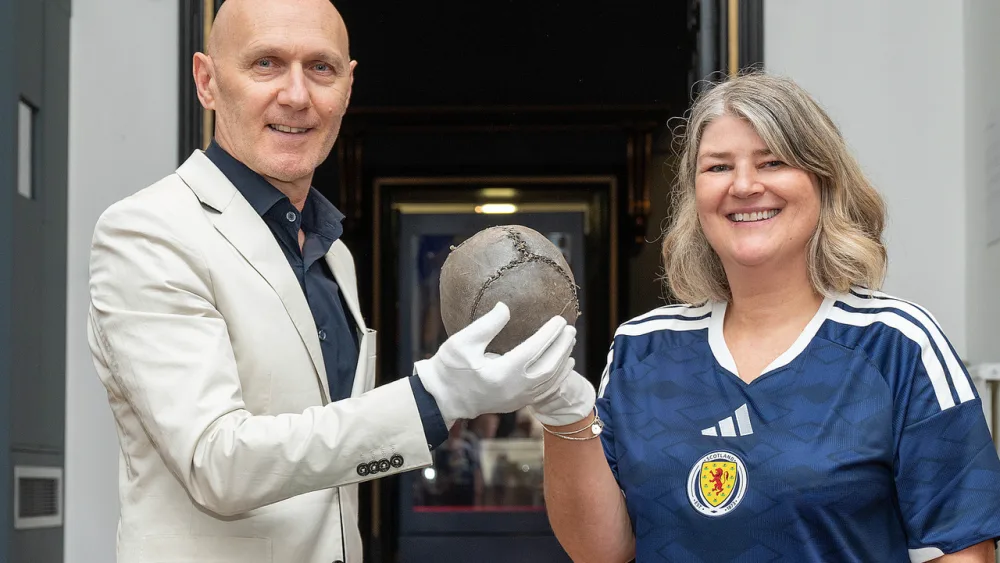 Dr Laszlo Kalman and Caroline Mathers smiling while both holding the football