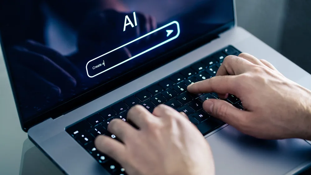 AI chat prompt on laptop screen with man's hands on keyboard